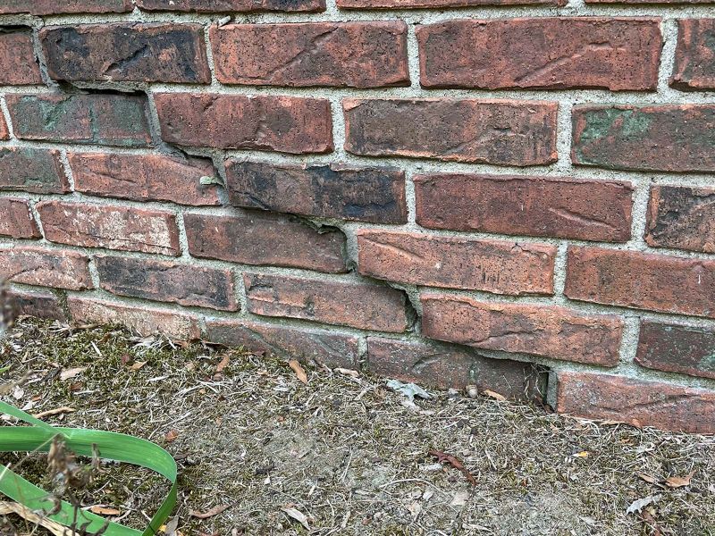 stair step crack in red brick at base of home